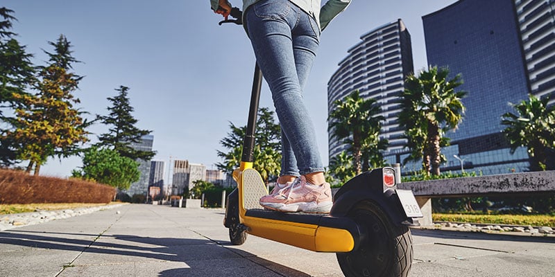 Casual modern woman using an electric scooter for eco-friendly riding through a tech park.